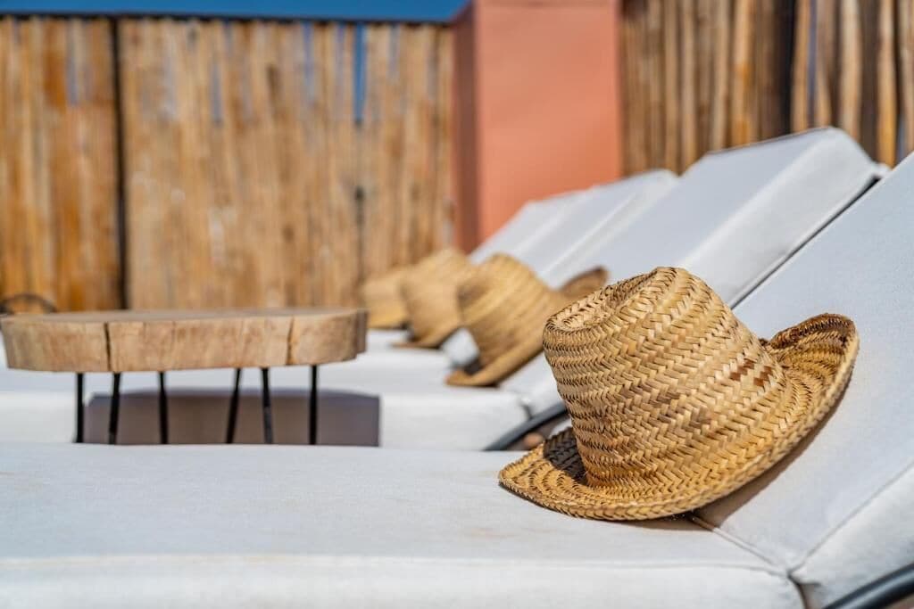 A row of lounge chairs with woven hats placed on them.