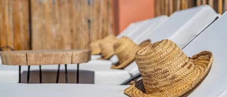 Sillas de descanso en hilera con sombreros tejidos encima.