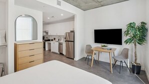 A modern room with a bed, a desk, a chair, a TV, and a plant. - Phoenix City Center Adventure Hub | Walkable & Resort-Style Amenities (Maricopa County)