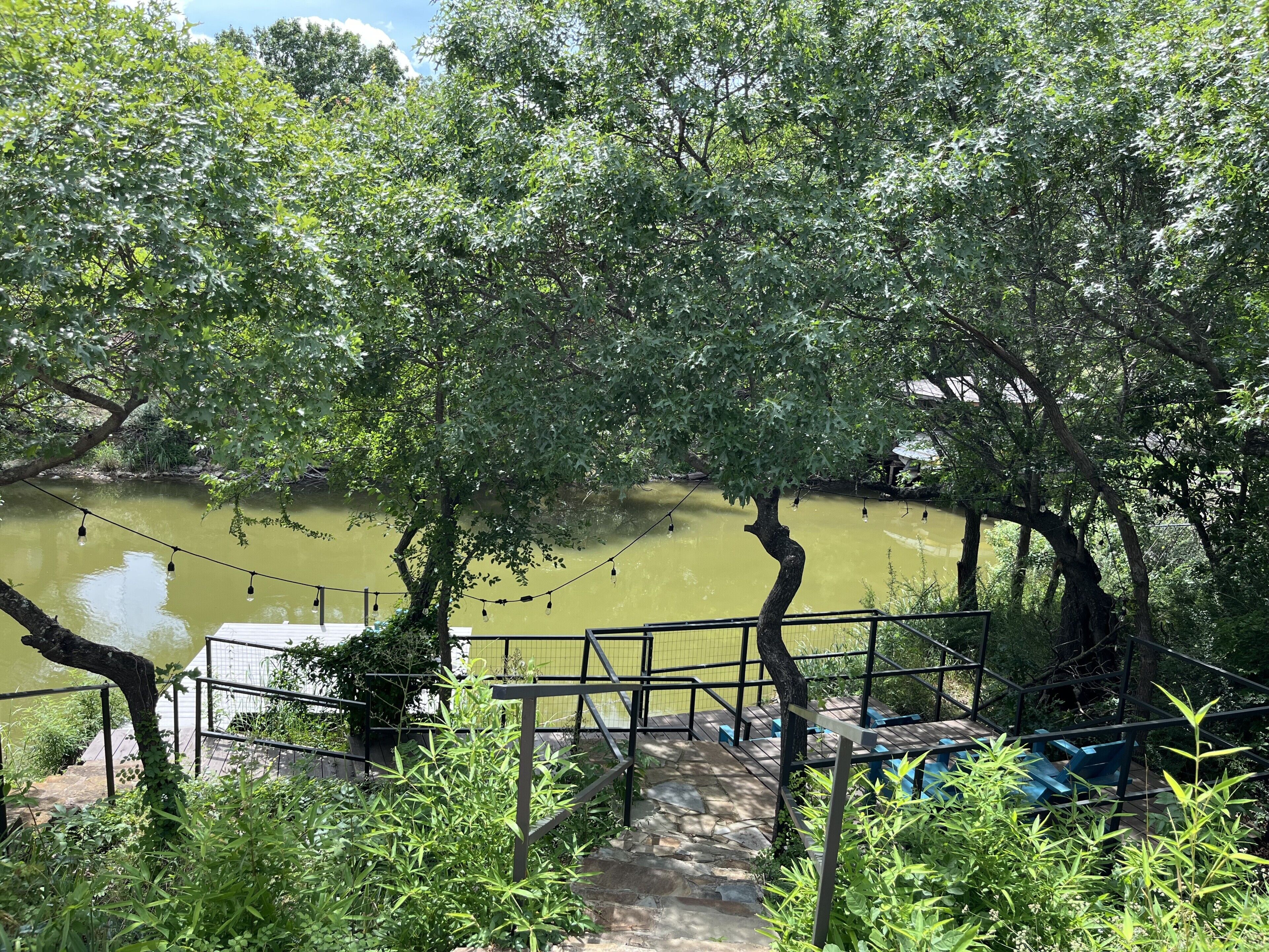 A wooden deck with a metal railing overlooking a body of water, surrounded by trees.