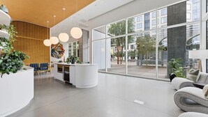 Moderni vastaanottoalue, jossa on kaareva valkoinen palvelutiski, istuimia ja suuret ikkunat.