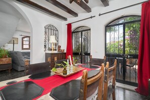 A dining area with a red tablecloth, wooden chairs, and a tray with glassware.