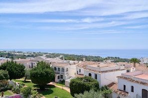 A coastal town with white buildings, a clear sky, and the sea in the background.