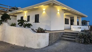 A modern house with a white exterior, a covered porch, and a stone retaining wall.