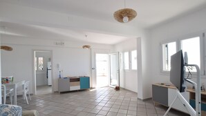 A spacious living area with a kitchen, dining table, and a television.