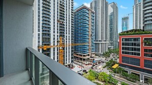 A high-rise building with multiple floors, a construction crane, and a red building with a sign. - Stylish Studio Steps from Brightline & Downtown (Miami)