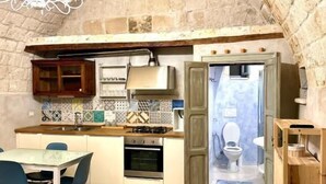 A compact kitchen with a dining area, a built-in oven, and a stone arch ceiling. - DIMORA DI LEO (Bisceglie)