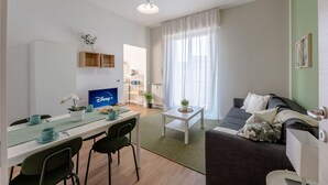 A modern living room with a dining area, a flat-screen TV, a sofa, and a coffee table. - [Penthouse panoramic view] Sea 3 min • A/C • WiFi (Albisola Superiore)