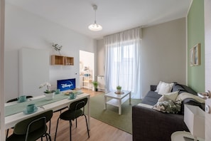 Una sala de estar moderna con comedor, un televisor de pantalla plana, un sofá y una mesa de centro.