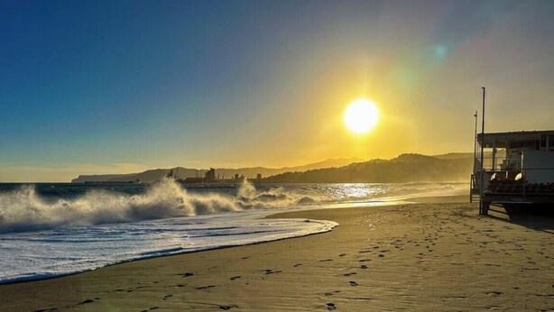 A beach with waves, a lifeguard tower, and a clear sky. - [Penthouse panoramic view] Sea 3 min • A/C • WiFi (Albisola Superiore)