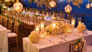 An outdoor dining area with tables set for a formal event, featuring candles, floral centerpieces, and hanging lights. - Brand New Island Villa 4B+Pool Full sea view (Fujairah)