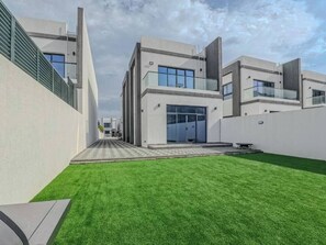 Un edificio moderno con techo plano, amplias ventanas y un césped bien cuidado.