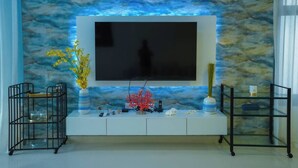 A modern living room with a mounted TV, a white console table, and decorative items. - Brand New Island Villa 4B+Pool Full sea view (Fujairah)