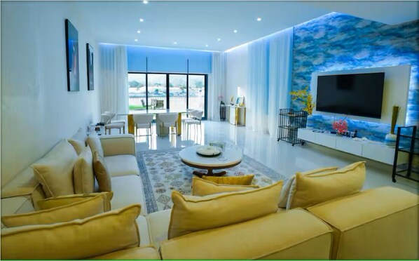 Una sala de estar moderna con un conjunto de sofá, una mesa de centro, un televisor de pantalla plana y un ventanal con vistas.