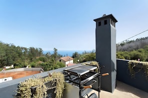 Una terrazza sul tetto con una griglia, un camino e vista sul mare.