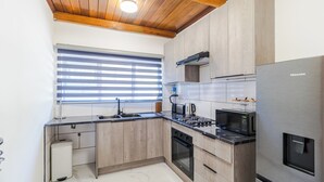 A modern kitchen with wooden cabinets, a stainless steel refrigerator, a microwave, and a built-in oven. - Boutique Hotel-Style Room In Ferndale-G7 (Randburg)