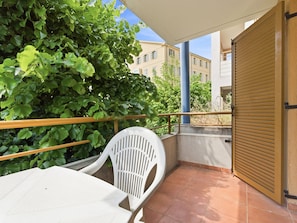 A balcony with a white chair, a table, a wooden railing, and a closed door. - Functional Holiday Base in Grasse (Grasse)