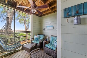 Eine überdachte Veranda mit Korbmöbeln, Deckenventilator und rustikalem Dekor.