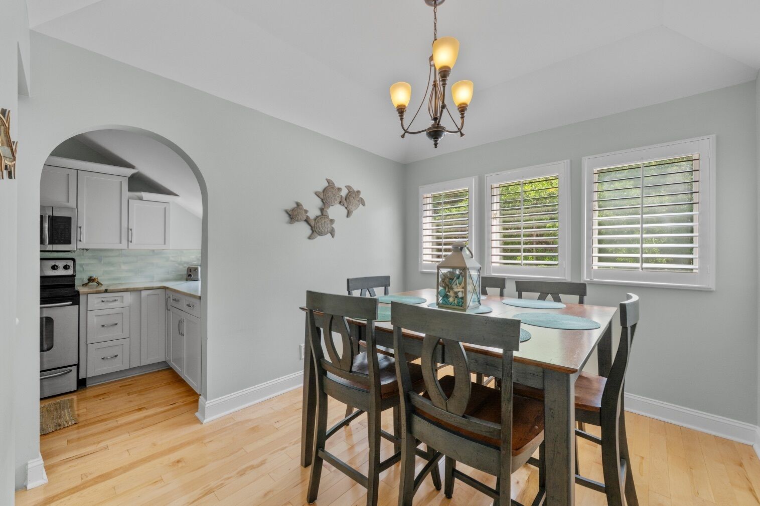 A kitchen with white cabinets, a wooden dining table with chairs, and a chandelier.