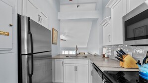 Una cocina moderna con armarios blancos, electrodomésticos de acero inoxidable y una tabla de cortar de madera.