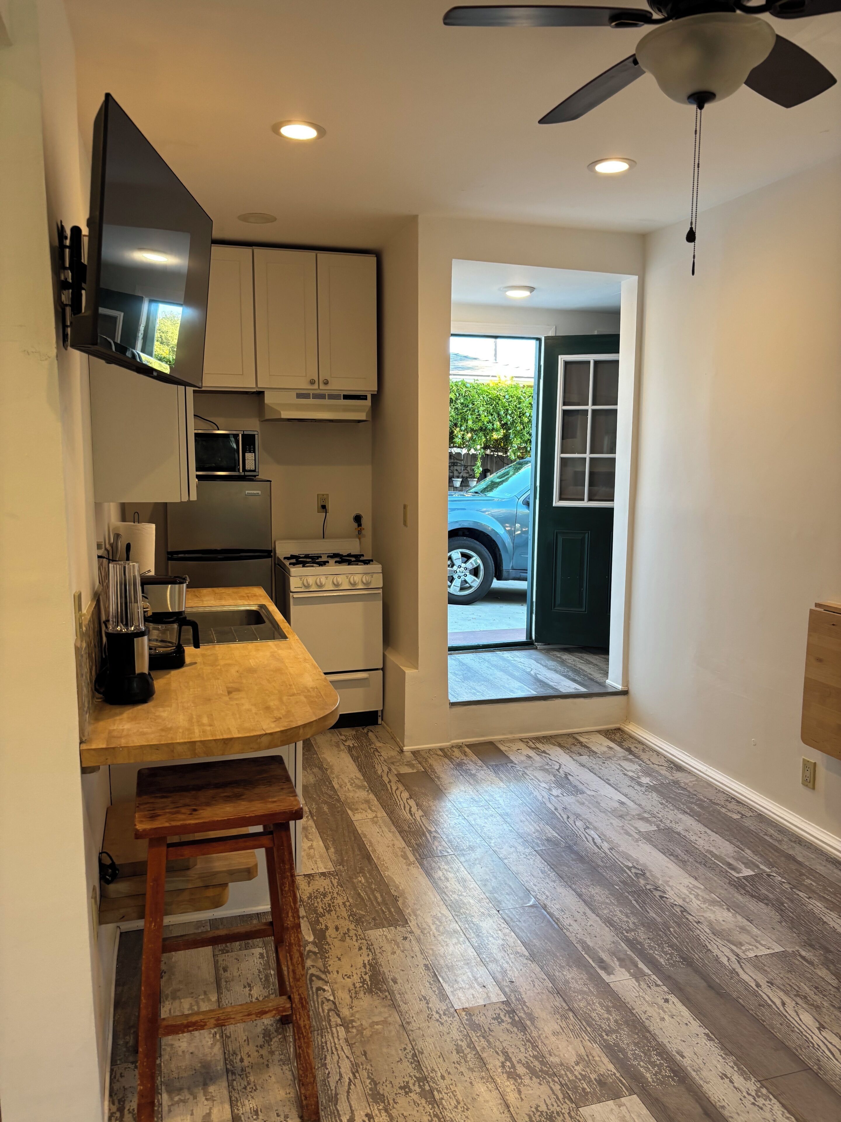 A compact kitchen with a microwave, stove, and a ceiling fan.