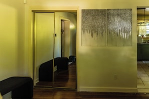 A hallway with a mirrored wall, a black chair, and a kitchen area in the background. - Lisa's Ranch (Richmond)