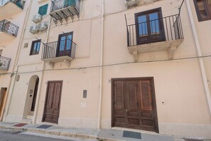 A multi-story building with balconies, large wooden doors, and air conditioning units. - Apartment 'Le Caravelle - Apt 2' (Castellammare del Golfo)