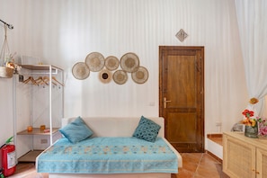 Een kamer met een bed, een houten deur, een wandplank en een hangmand.