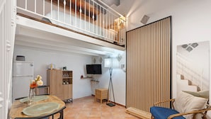A compact living space with a dining table, chairs, a television, a floor lamp, a sofa, and a staircase. - Apartment 'Le Caravelle - Apt 36' (Castellammare del Golfo)