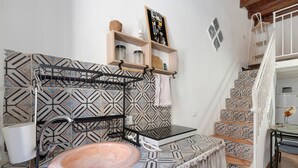 A bathroom with patterned tiles, a sink, a towel rack, shelves with toiletries, and a staircase with patterned tiles. - Apartment 'Le Caravelle - Apt 36' (Castellammare del Golfo)