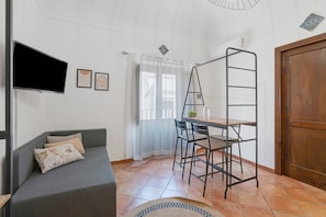 Una habitación con un sofá, un televisor, una escalera, una mesa y una puerta.