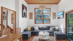 A modern living room with a wooden dining table, a large window, a ceiling fan, and a cozy seating area. - Fire Island Pines paradise (Fire Island)