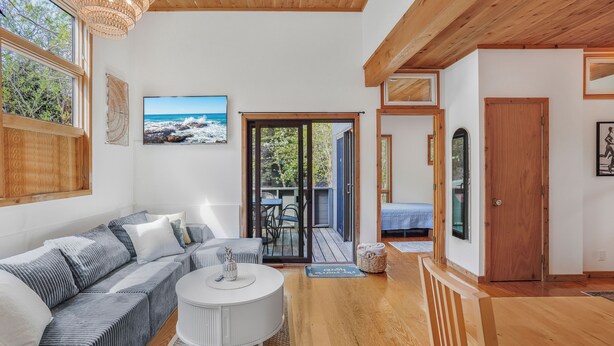 A modern living room with a sofa, a round table, and a view of the outdoors. - Fire Island Pines paradise (Fire Island)