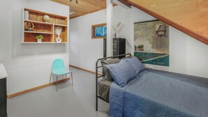 A bedroom with a bunk bed, a desk with a chair, a wooden shelf with decorative items, and a poster on the wall. - Fire Island Pines paradise (Fire Island)