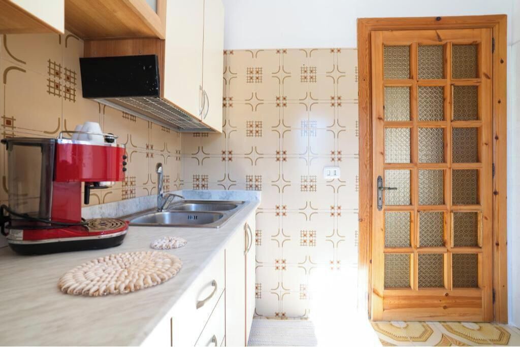 A kitchen with a coffee maker, a sink, and a patterned backsplash.