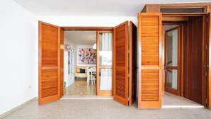 Een kamer met een houten deur, een witte muur en een betegelde vloer.