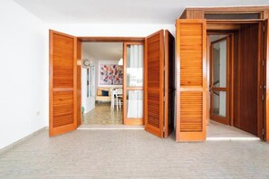 Ein Zimmer mit Holztür, weißer Wand und Fliesenboden.