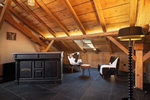 A cozy room with a wooden ceiling, a fireplace, a bar area, and two chairs. - Stone Lodge - 8 pers - Sauna - Bain nordique (Gérardmer)