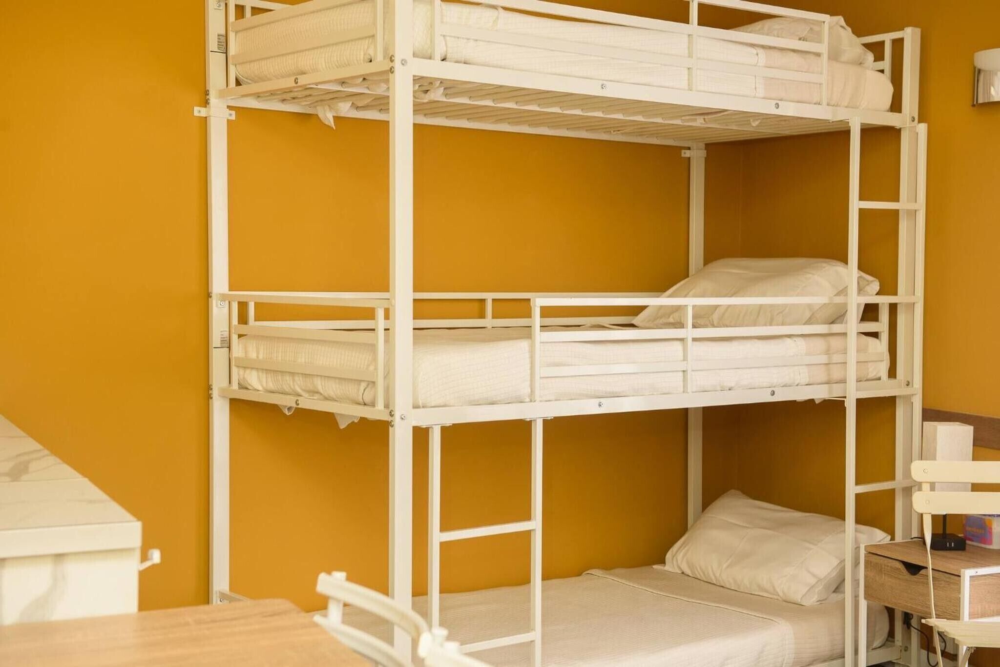 Dormitorio con literas, un escritorio de madera y una silla.