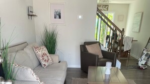 A living room with a sofa, a coffee table, a rug, and a staircase leading to another room. - Welcome to Bearly Behaving! (Candler)