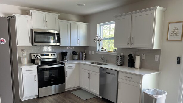 A modern kitchen with white cabinets, stainless steel appliances, and a window. - Welcome to Bearly Behaving! (Candler)