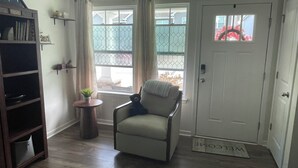 A living room with a sofa, a small table with a plant, a bookshelf, and a door with a welcome mat. - Welcome to Bearly Behaving! (Candler)
