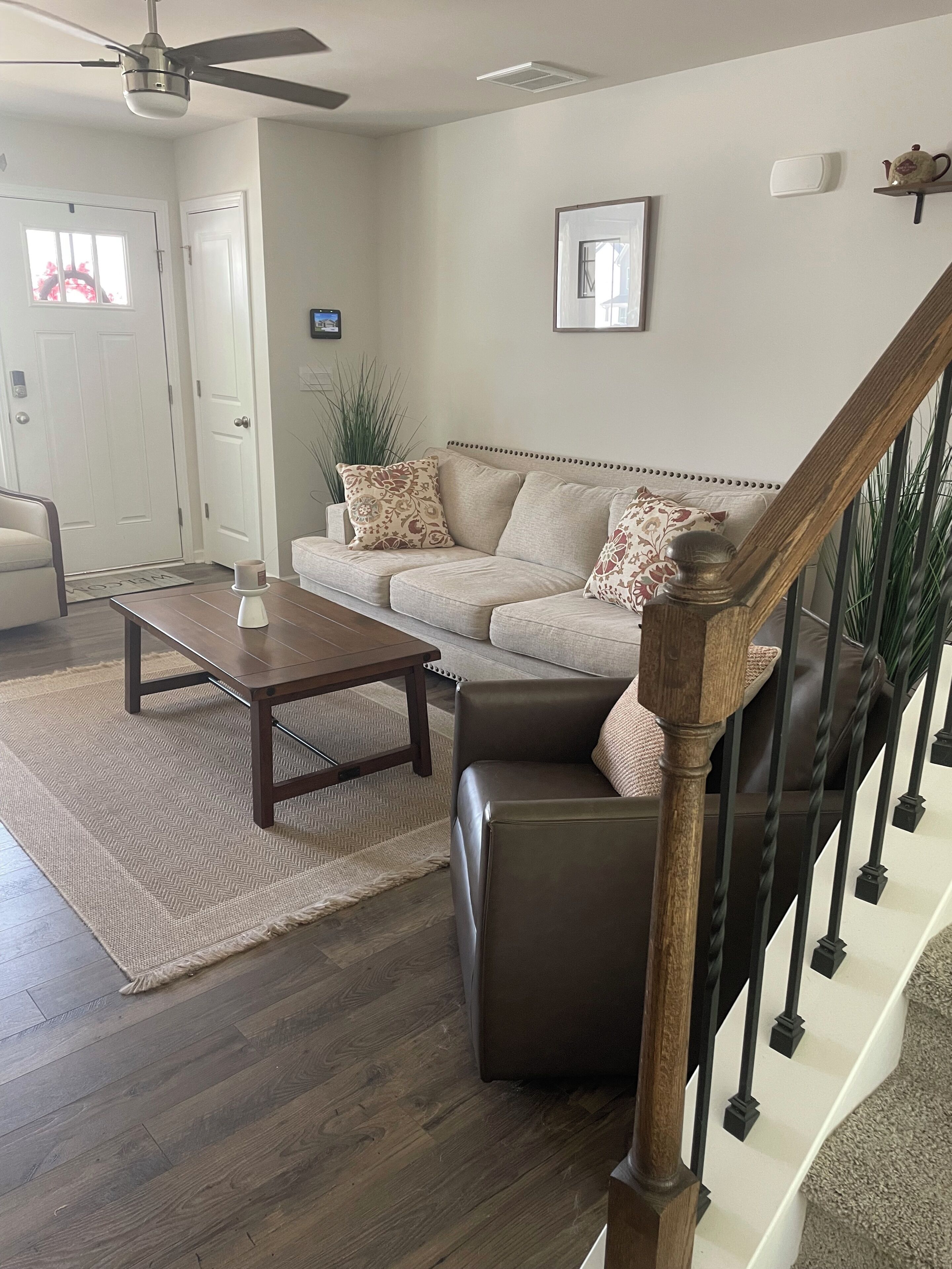 A living room with a sofa, coffee table, and a staircase with a railing.