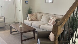 A living room with a sofa, coffee table, and a staircase with a railing. - Welcome to Bearly Behaving! (Candler)