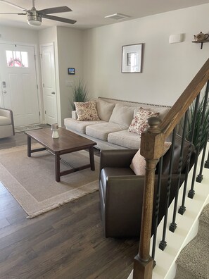 Ein Wohnzimmer mit einer Couch, einem Couchtisch und einer Treppe mit Geländer.