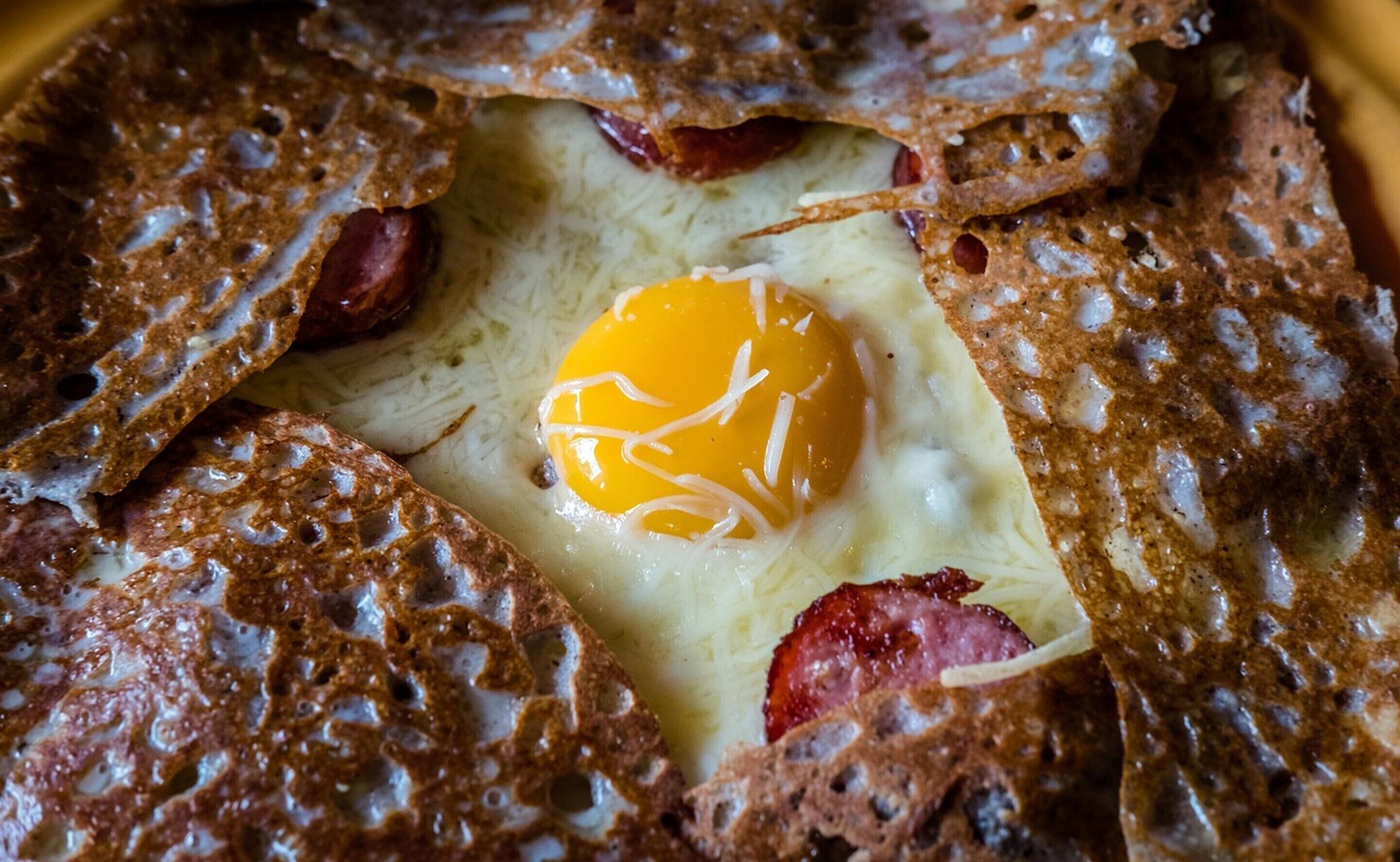A breakfast dish with an egg, bacon, and toast.
