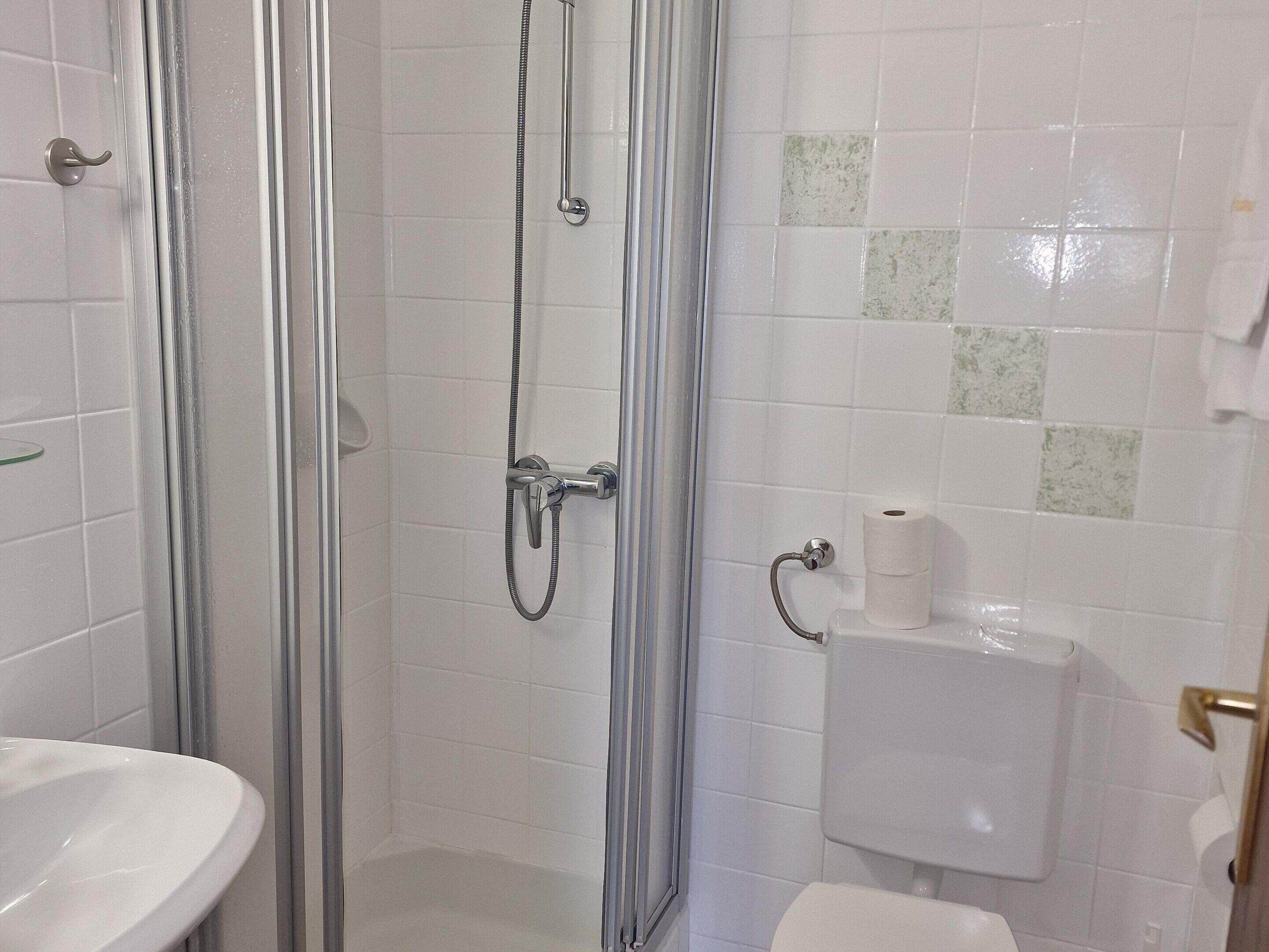 Un baño con cabina de ducha de vidrio, un lavamanos blanco y un inodoro.