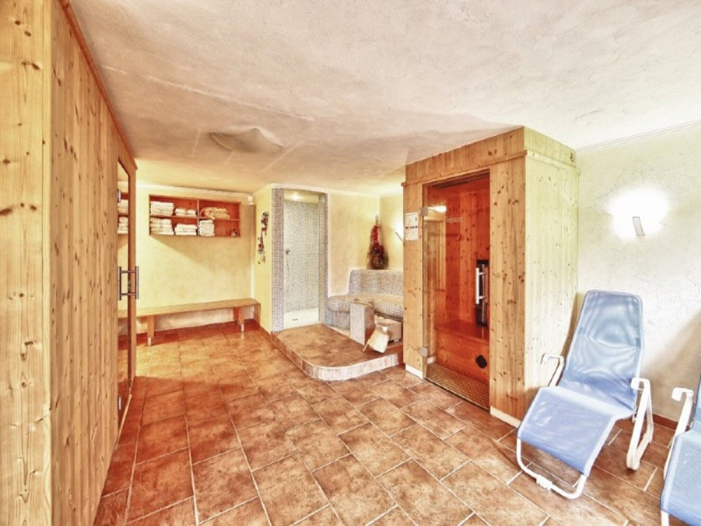 Ein Zimmer mit einer hölzernen Bank, einer kleinen Sitzecke und einer Tür zu einem weiteren Raum.
