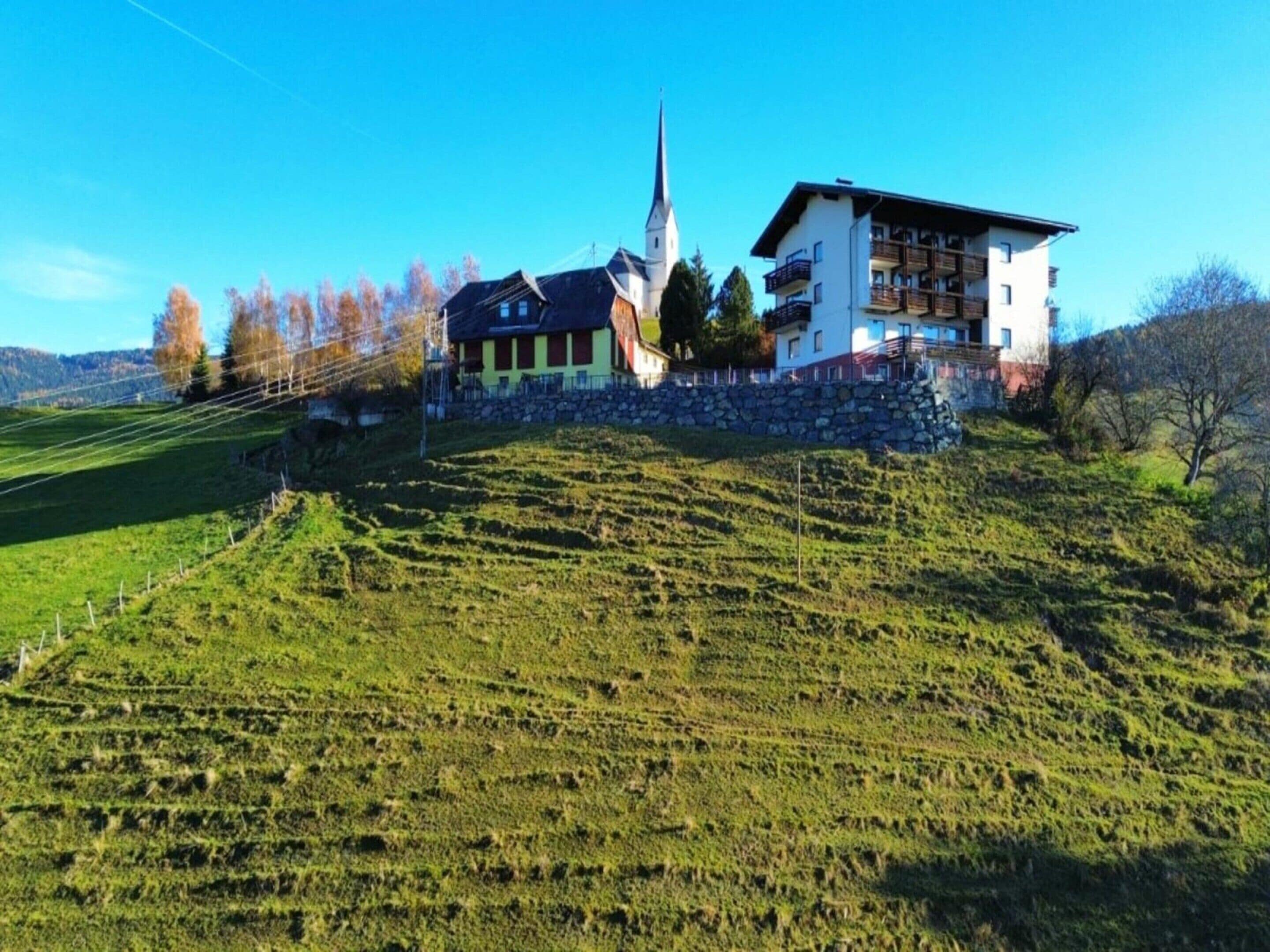 Ein Gebäude mit Kirchturm, Steinmauer und einem modernen Bauwerk mit Balkonen.