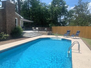 A backyard with a swimming pool, a patio with chairs, and a wooden fence. - Relax, Swim & Unwind at Bella Casa's Private Pool Retreat Sleeps 6 Pet friendly (Valdosta)